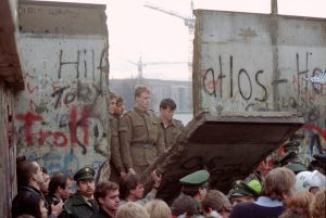 Alcune guardie di confine della Germania Est guardano cadere un pezzo di Muro alla Porta di Brandeburgo, l'11 novembre 1989. (AP Photo/Lionel Cironneau, File)